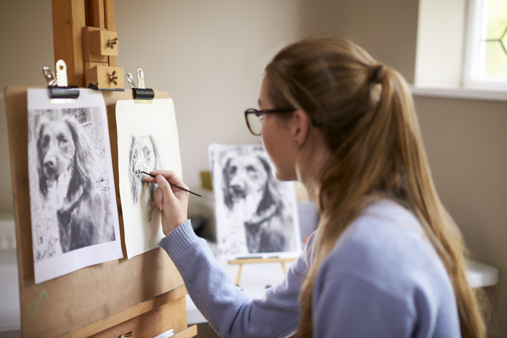 Why do an EPQ? If you're into art, you could create an artefact for your EPQ, like this teenage girl sitting at an easel and sketching a dog.
