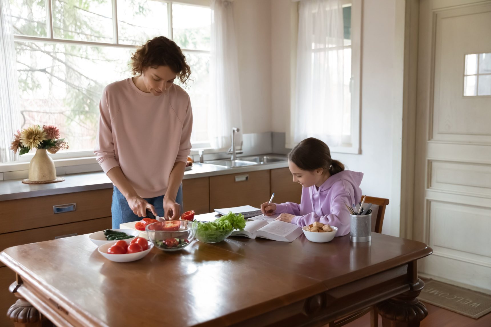 A teenage girl preparing for an exam whilst her mum cooks a healthy meal.