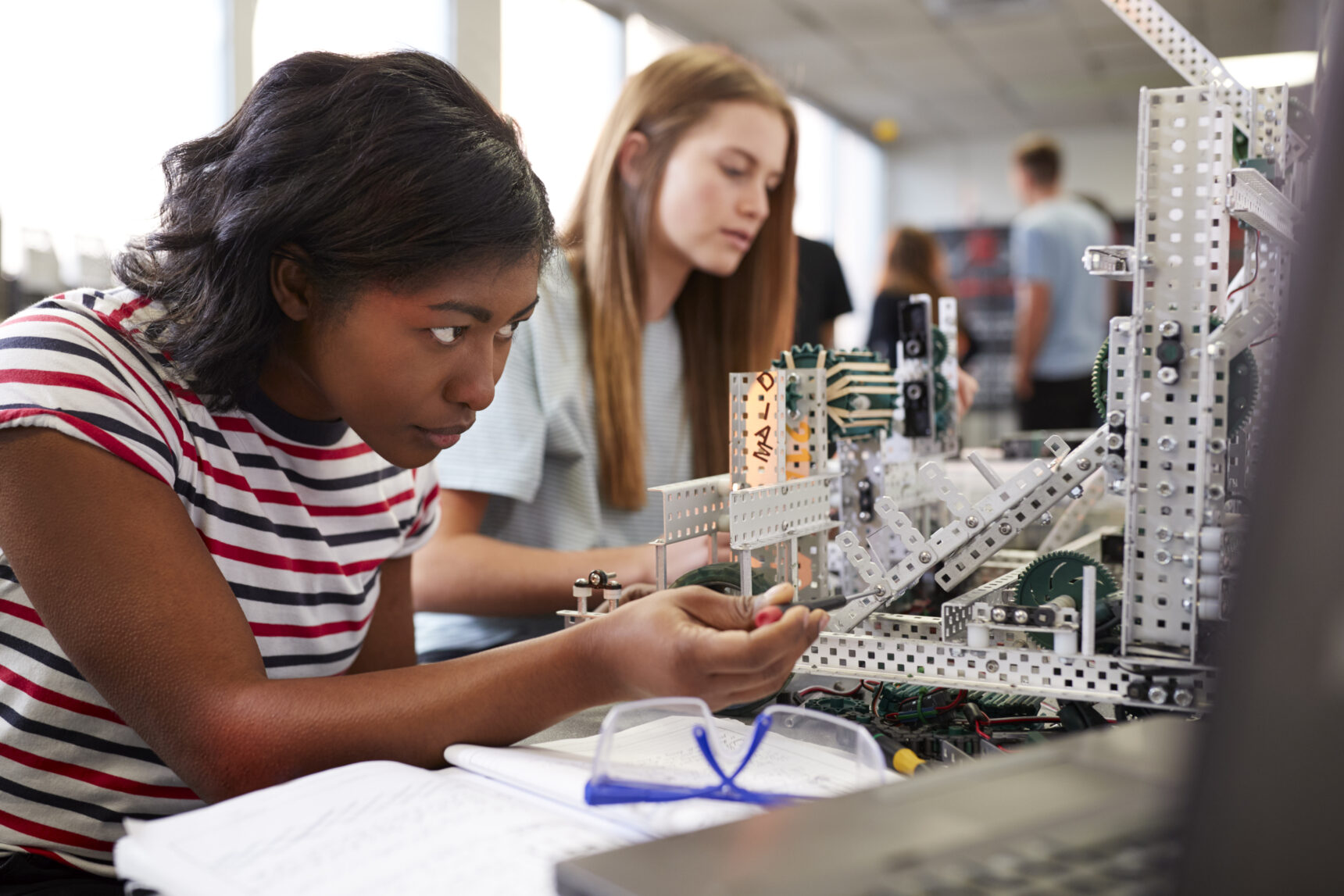 Two female STEM university students building a robot in engineering class.