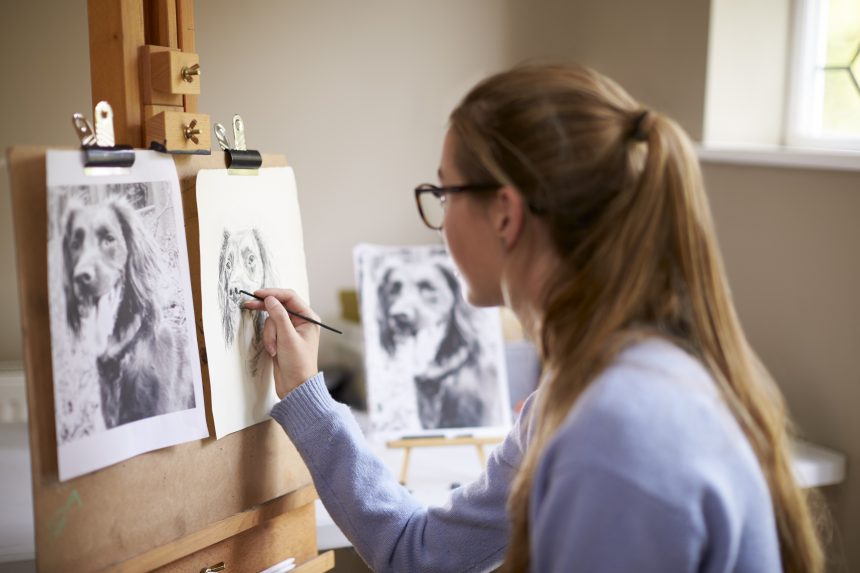 A teenage girl sitting at an easel and drawing for her EPQ project.