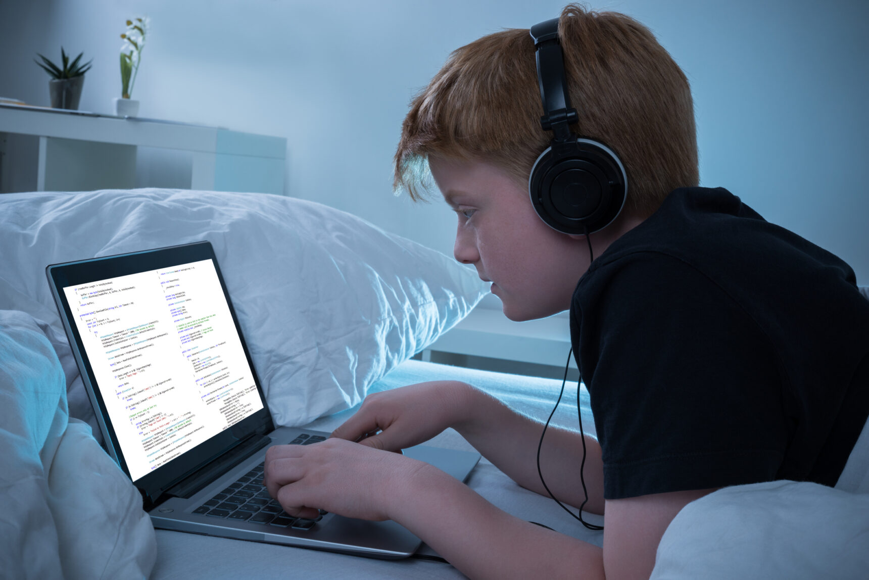 A teenage boy listening to music whilst learning to code.