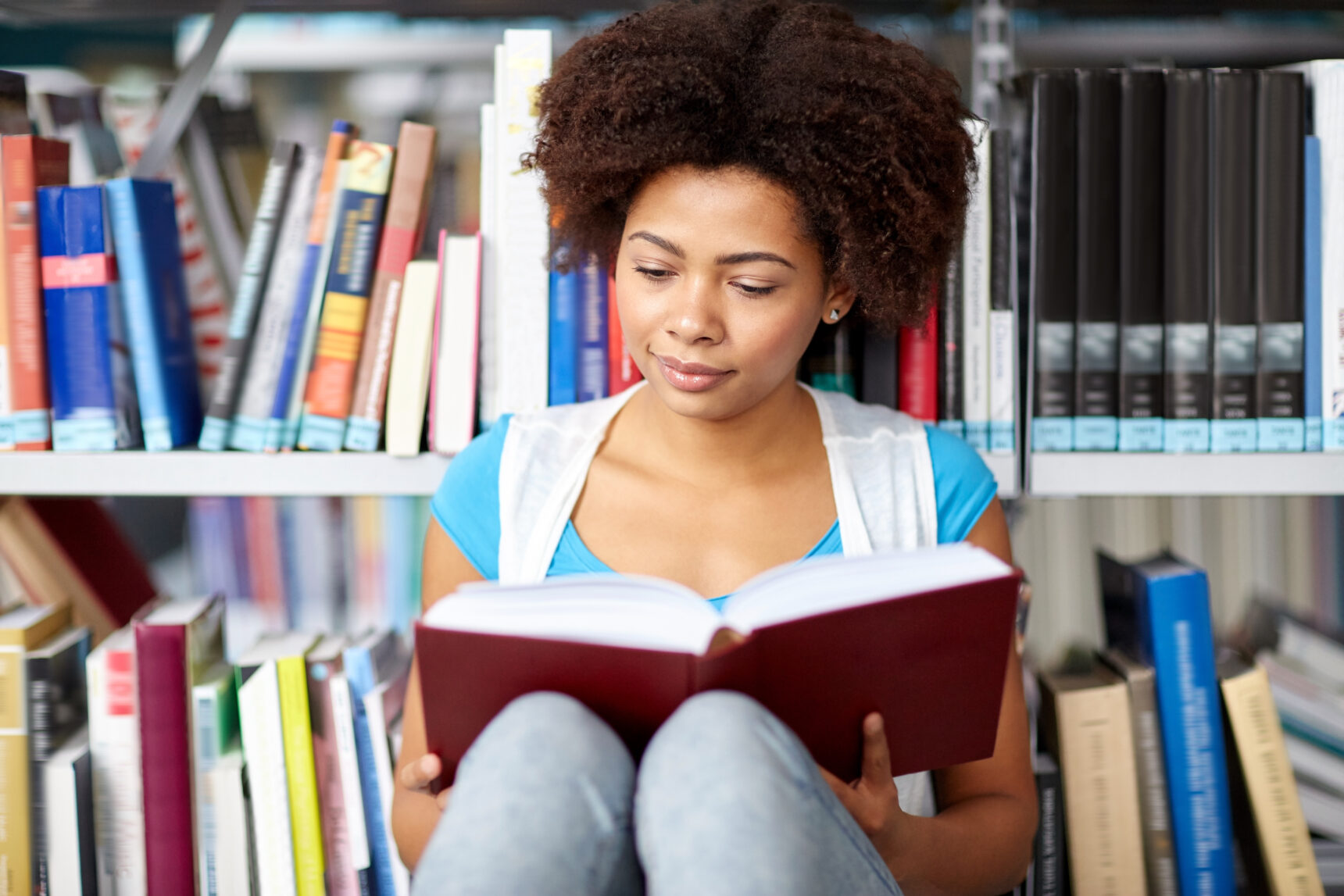 A female sixth-form student reading a STEM book in the library.