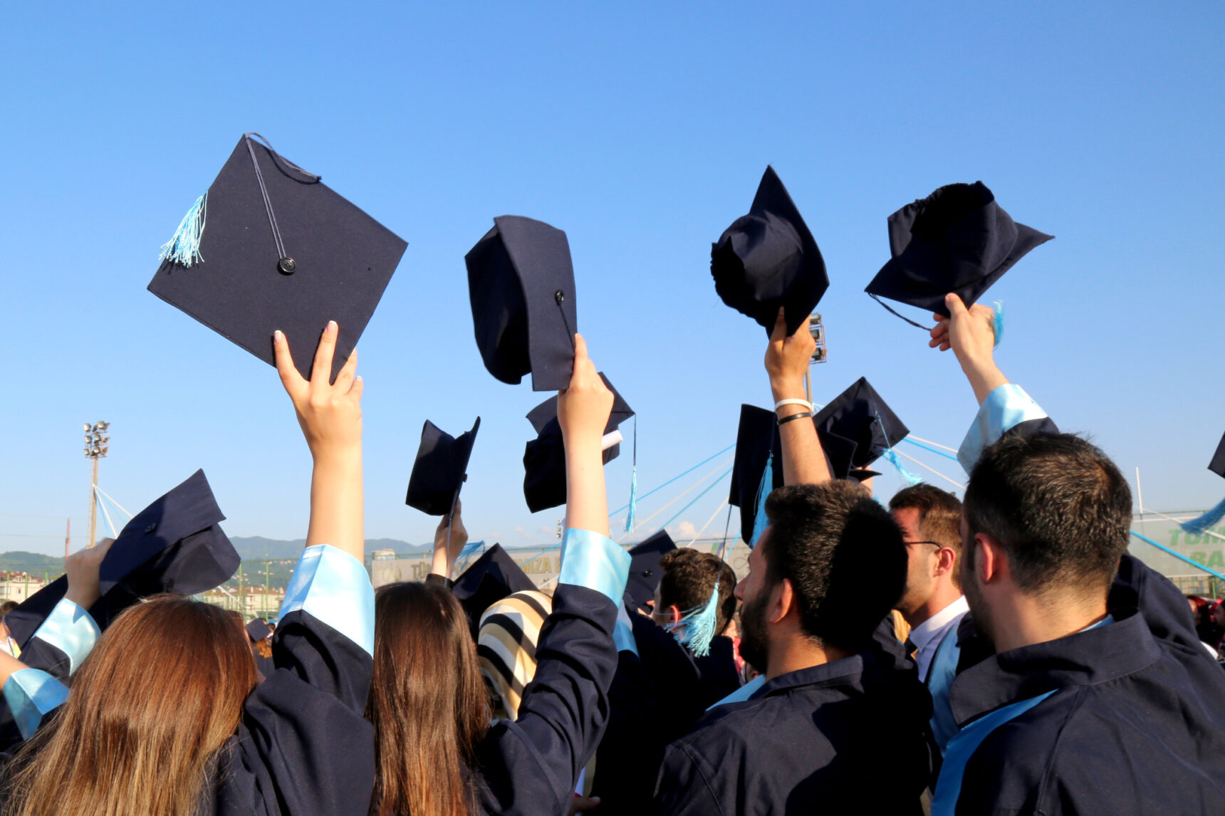 Group of students graduating and holding their graduation caps in the air.