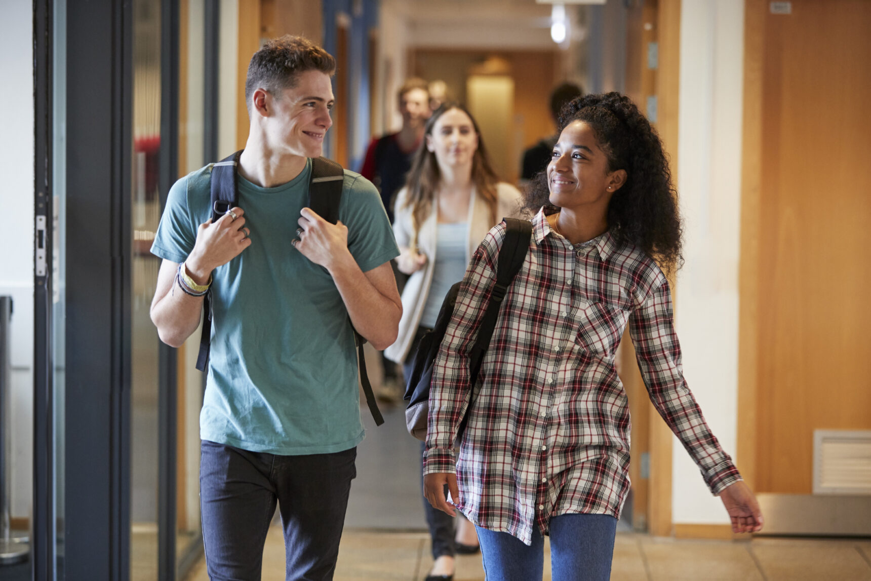 IB Diploma Programme students smiling and walking down corridor.