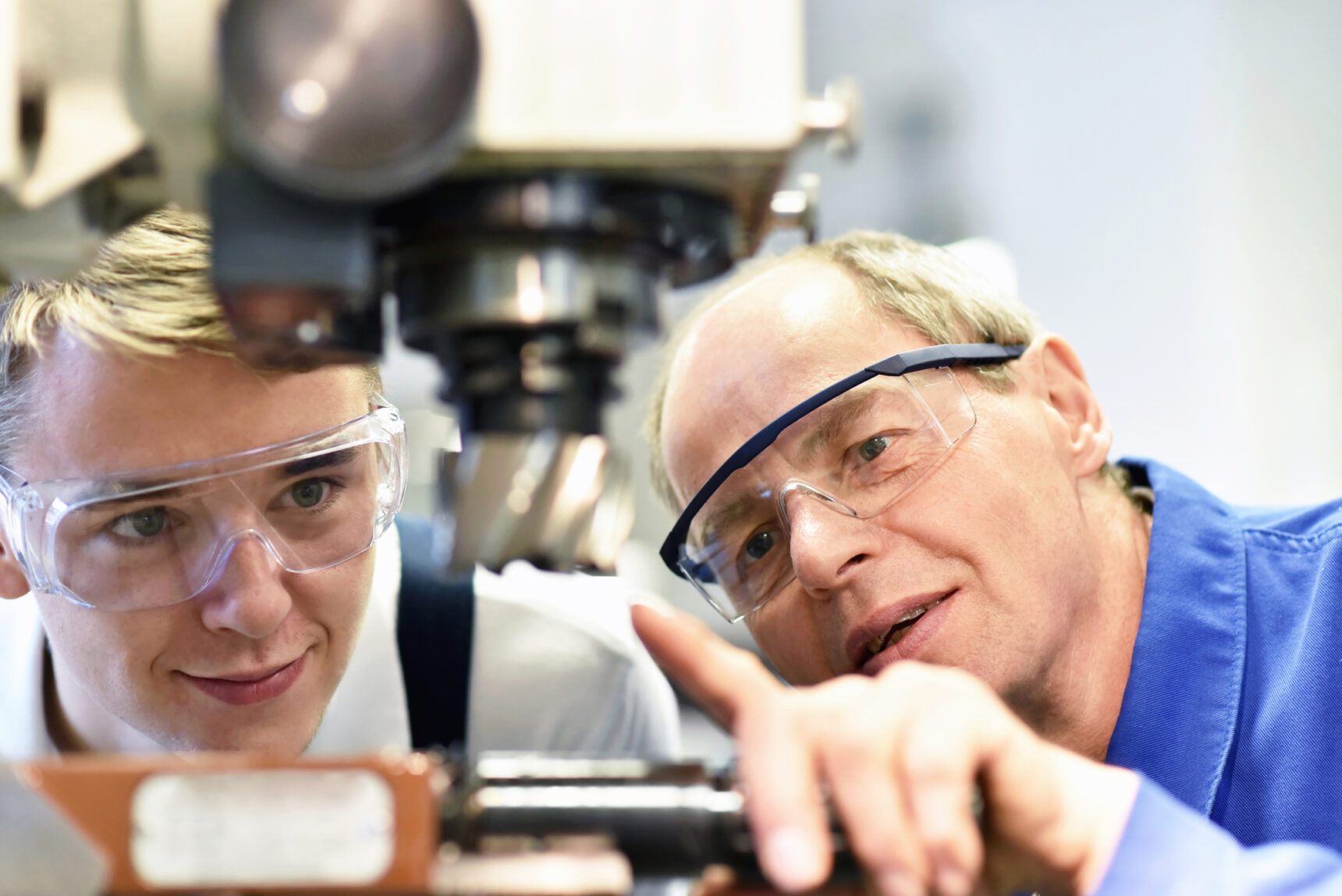 Teacher explains details of a milling machine in on-the-job training on the NVQ