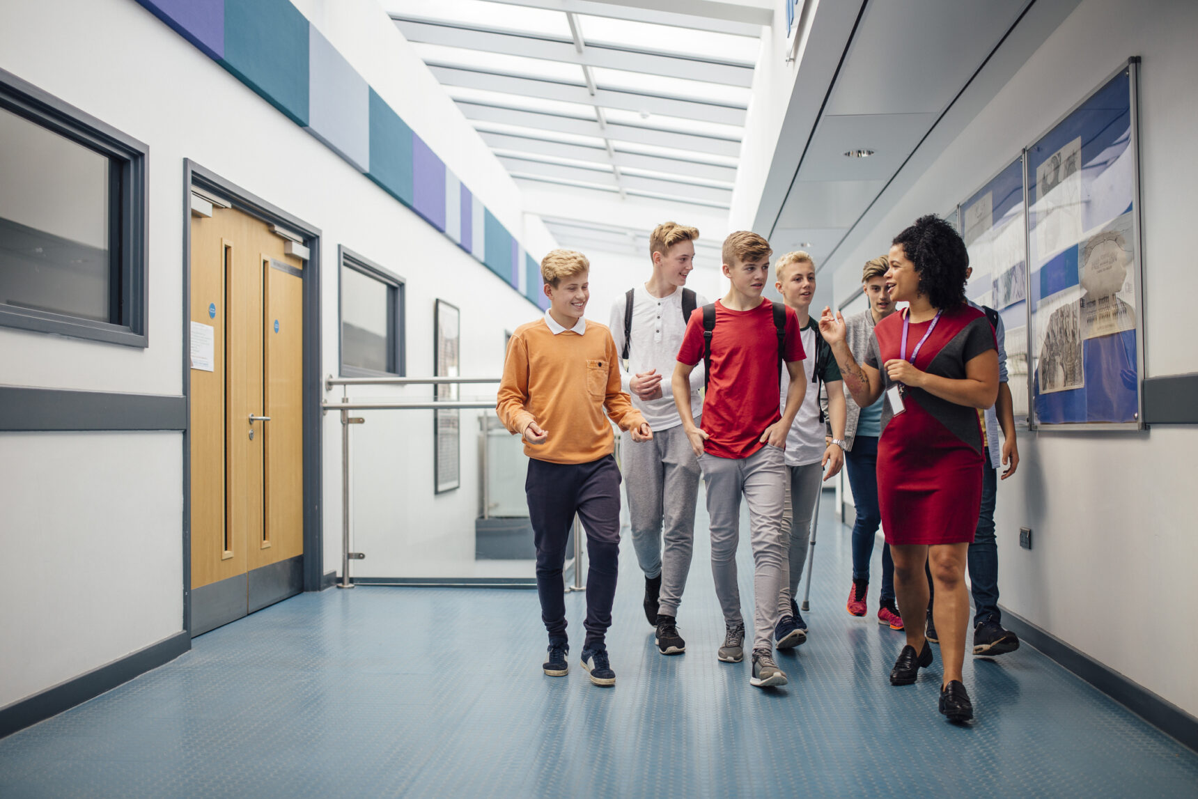 Female teacher is giving a group of STEM BTEC students a tour of the school on open day.