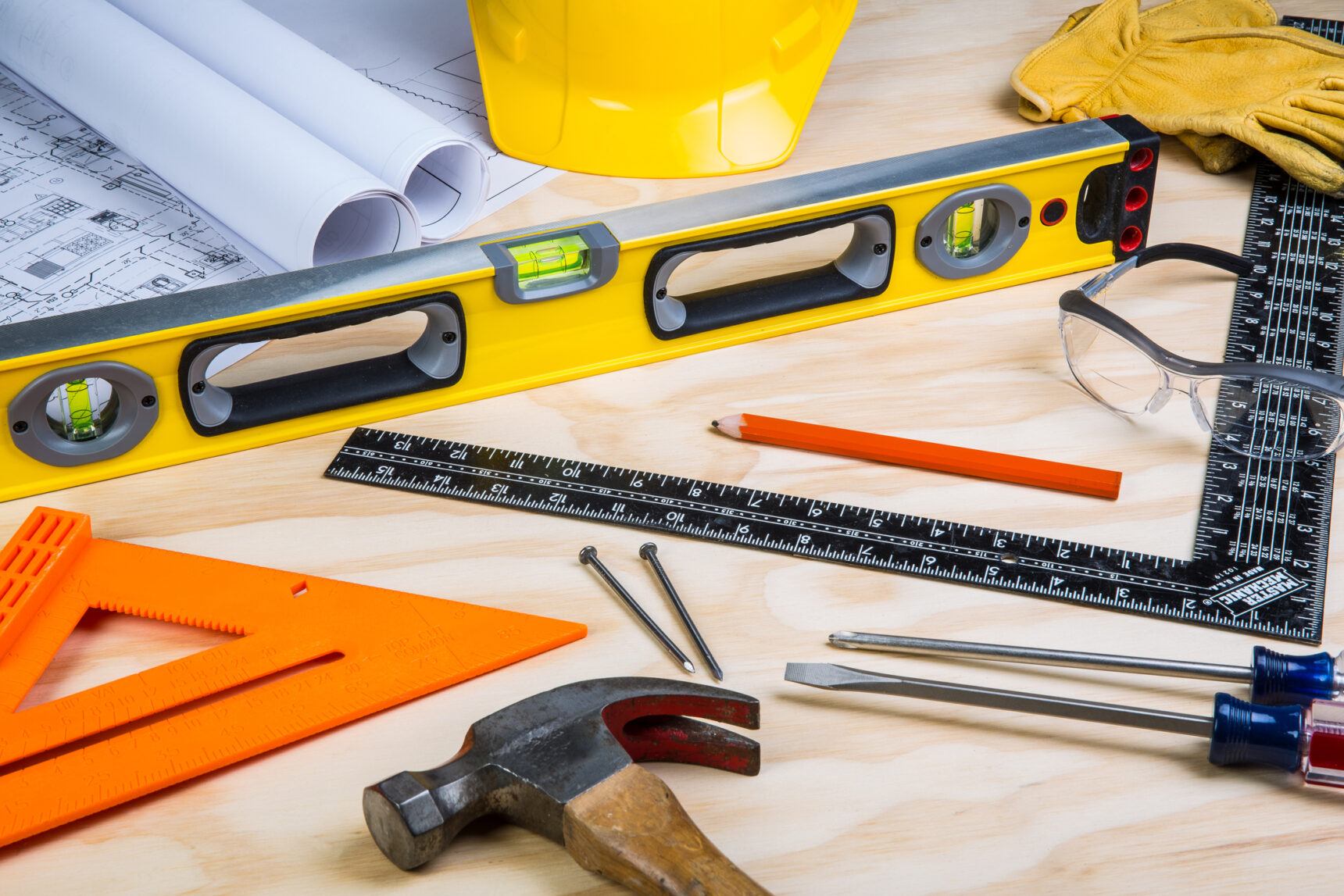 Construction tools randomly placed on a wooden background.