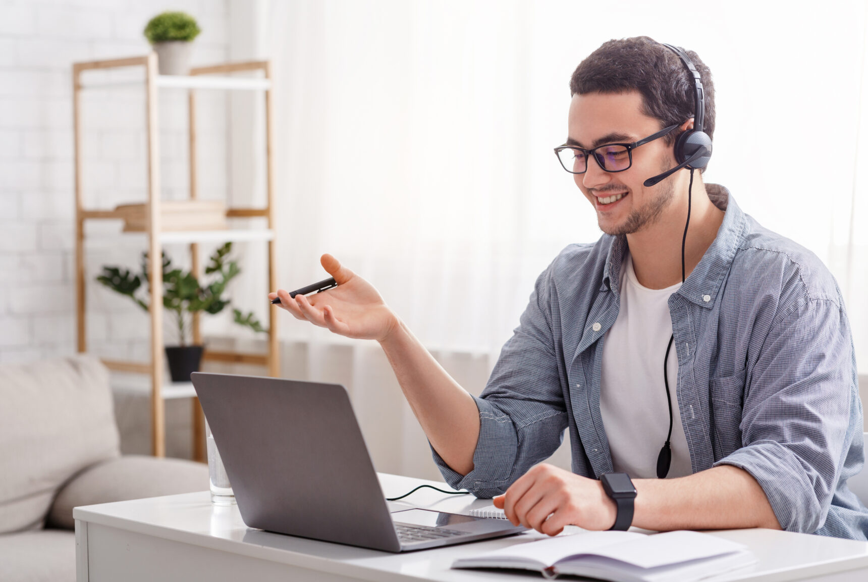 A male tutor conducting an online lesson using his computer and headphones