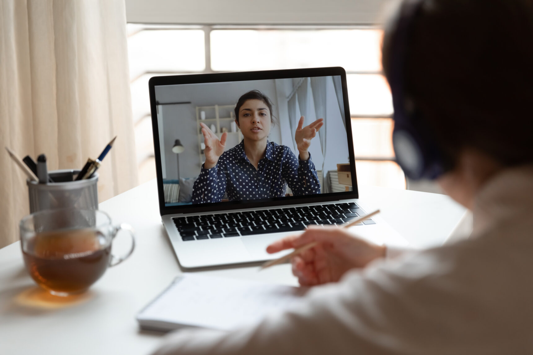 Online female tutor pictured on a laptop asking questions to their student.