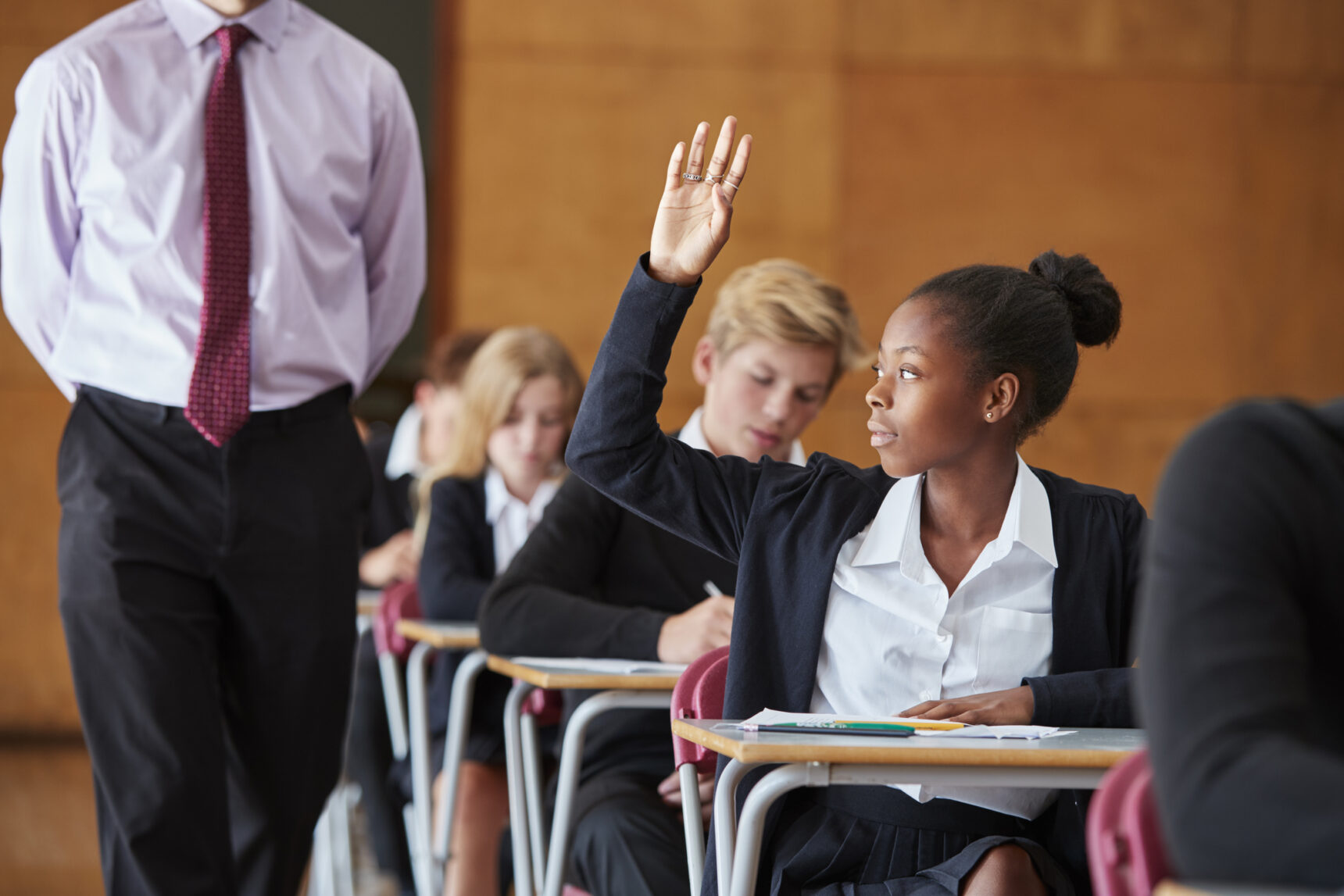 Student with her hand up during a GCSE exam.